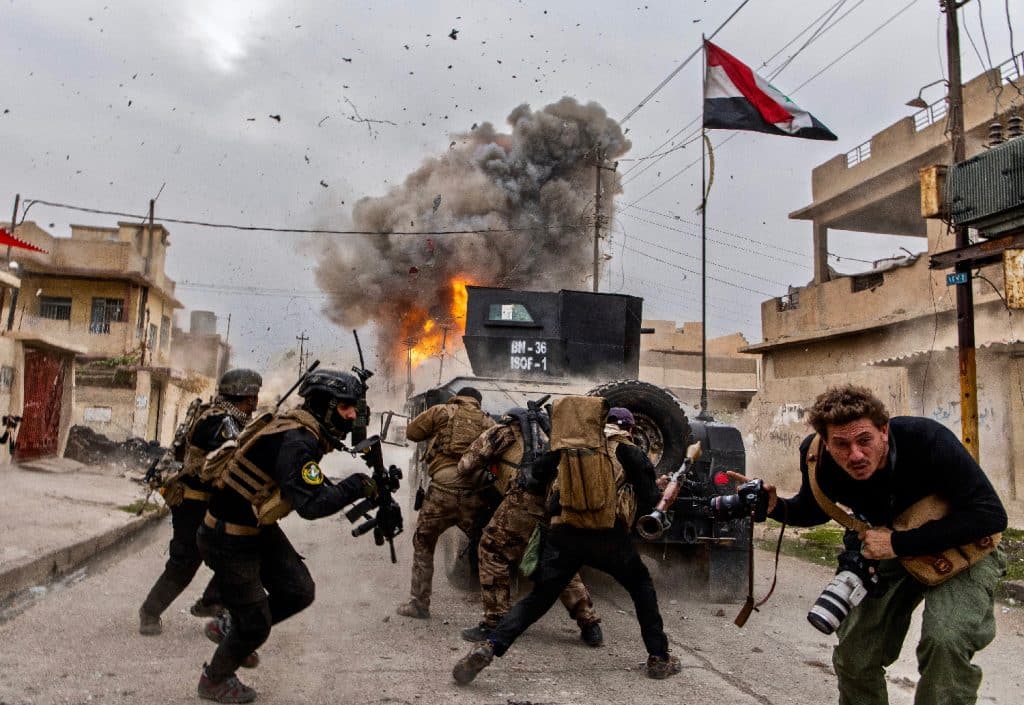 Iraq, 2016. Explosion of a suicide car at the front of a Golden Division column advancing into Mosul against the Islamic State. In the foreground, Antoine Chauvel, son of Patrick © Patrick Chauvel