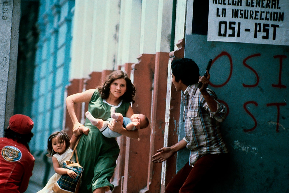 Salvador, 1980. A pregnant woman flees the gunfire with her children during the funeral of Archbishop Romero © Patrick Chauvel