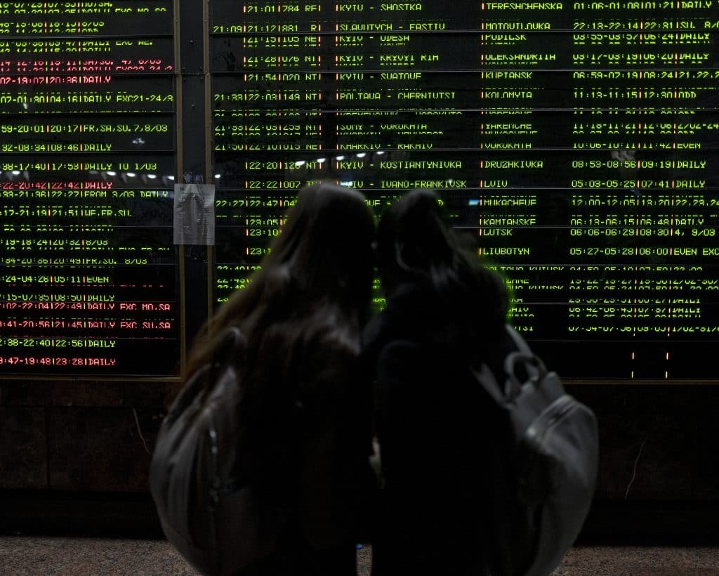 Ukrainian women look at the notice board in the hall of the Kyiv Central Railway Station on February 27, 2022. © Rafael Yaghobzadeh