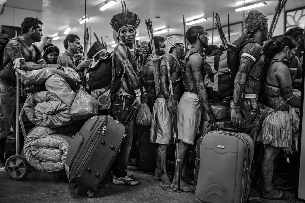 Mundurukus Indians line up to board a plane at Altamira Airport after protesting against the construction of the Belo Monte Dam on the Xingu River. The Mundurukus inhabit the banks of the Tapaj√≥s River, where the government has plans to build new hydroelectric projects. Even after counter pressure from indigenous people, environmentalists and non-governmental organizations, the Belo Monte project was built and completed in 2019. © Lalo de Almeida / Panos Pictures for Folha de São Paulo