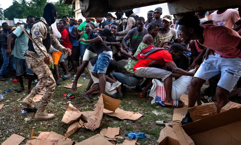 Chaos erupts as Haitian police try to control a desperate crowd at a food distribution site as residents cope with the aftermath of a massive earthquake in Maniche, Haiti on Monday August 23, 2021. Aid had been hampered by gang wars until a truce was declared to allow convoys to pass. The quake affected a large area of rural southwestern provinces, killing at least a confirmed 2,250 people and injuring 12,000. Countless families were displaced, leaving the Caribbean Island nation in the grip of yet another humanitarian crisis © Carol Guzy