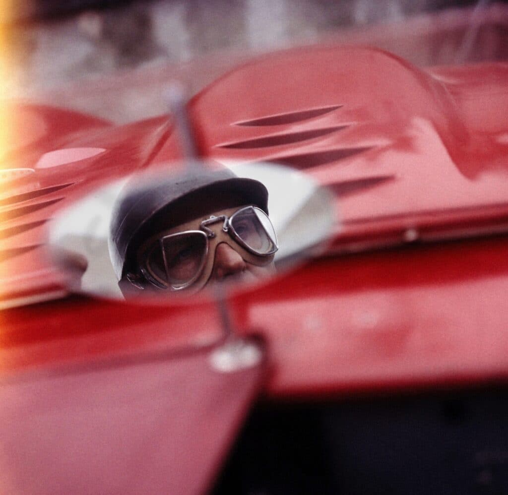 Face of auto racer Juan Manuel Fangio reflecting on a side mirrors, France, 1957.