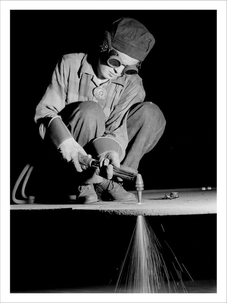 Ouvrière en train de souder une plaque d’acier à l’usine de Blindage de Gary. Gary, Indiana, États-Unis d’Amérique, 1943.