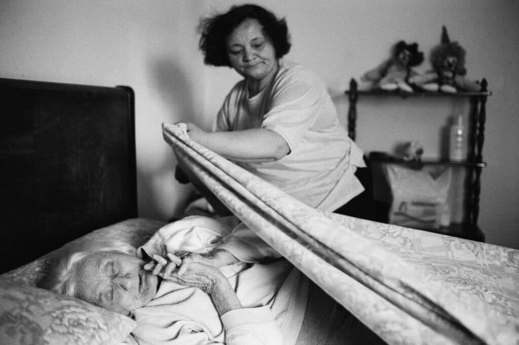 Darya, Ukrainienne, 56 ans, couche Augusta, 94 ans, une des quatre sœurs dont elle s’occupe en tant que « badante »(aide soignante). Bolzano, Italie, 2007 © Jane Evelyn Atwood