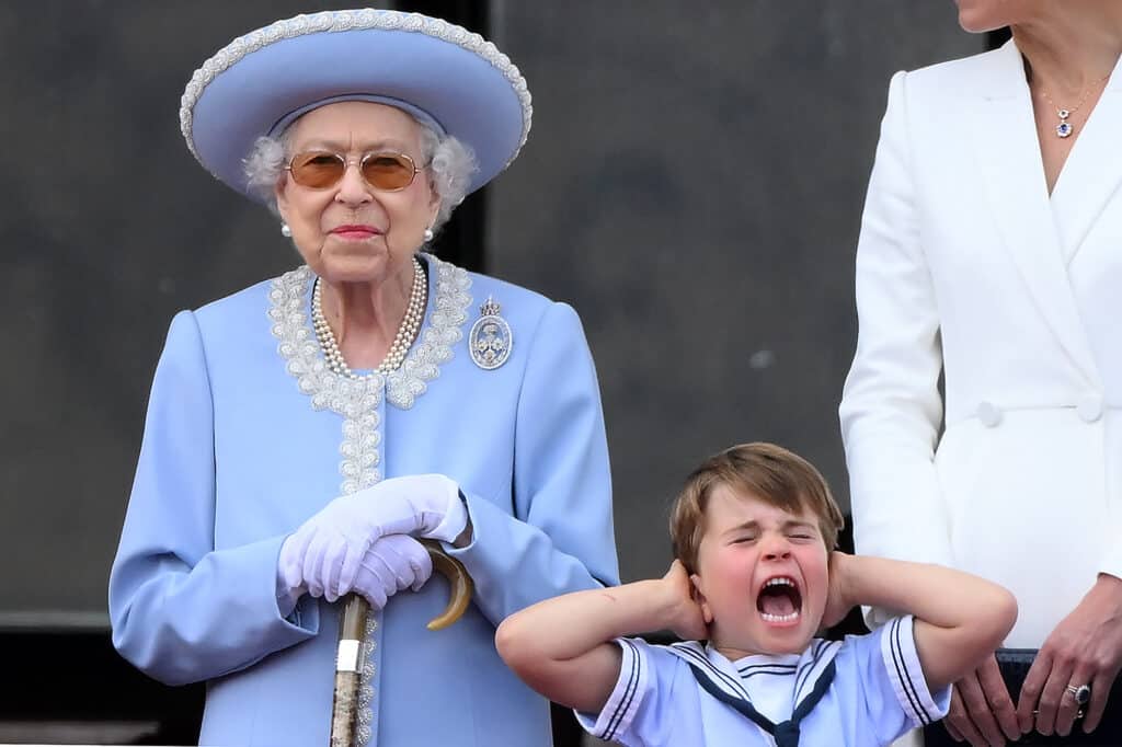 Le prince Louis de Cambridge (à droite) tient ses oreilles alors qu'il se tient à côté de la reine Elizabeth II pour assister à un défilé aérien spécial depuis le balcon du palais de Buckingham, après le défilé de l'anniversaire de la reine, le Trooping the Colour, dans le cadre des célébrations du jubilé de platine de la reine Elizabeth II, à Londres, le 2 juin 2022. © Daniel LEAL / AFP