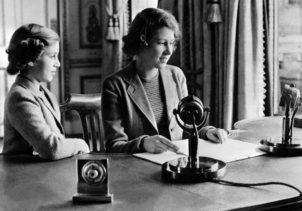 Sur cette photo d'archive prise le 1er octobre 1940 à Windsor, on voit la Princesse Elizabeth (future Reine Elizabeth II) et sa sœur la Princesse Margaret envoyer un message pendant le programme pour enfants de la BBC, en particulier aux enfants qui étaient évacués à cause de la Seconde Guerre mondiale. © POOL / AFP