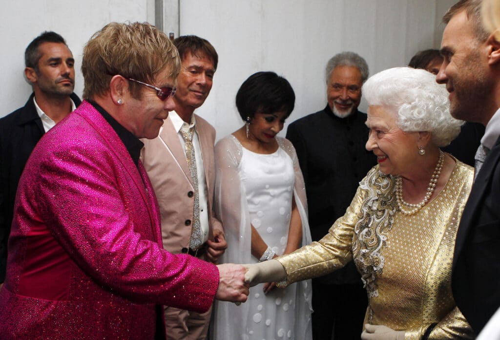 La reine Elizabeth II rencontre Sir Elton John dans les coulisses sous le regard du chanteur britannique Robbie Williams, à droite, lors du concert du jubilé de diamant devant le palais de Buckingham à Londres, le 4 juin 2012. © AFP PHOTO / Dave Thompson