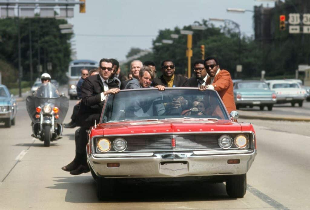 Bobby Kennedy campaigns in Indiana during May of 1968, with various aides and friends: former prizefighter Tony Zale and (right of Kennedy) N.F.L. stars Lamar Lundy, Rosey Grier, and Deacon Jones. ©Bill Eppridge Courtesy of Monroe Gallery of Photography