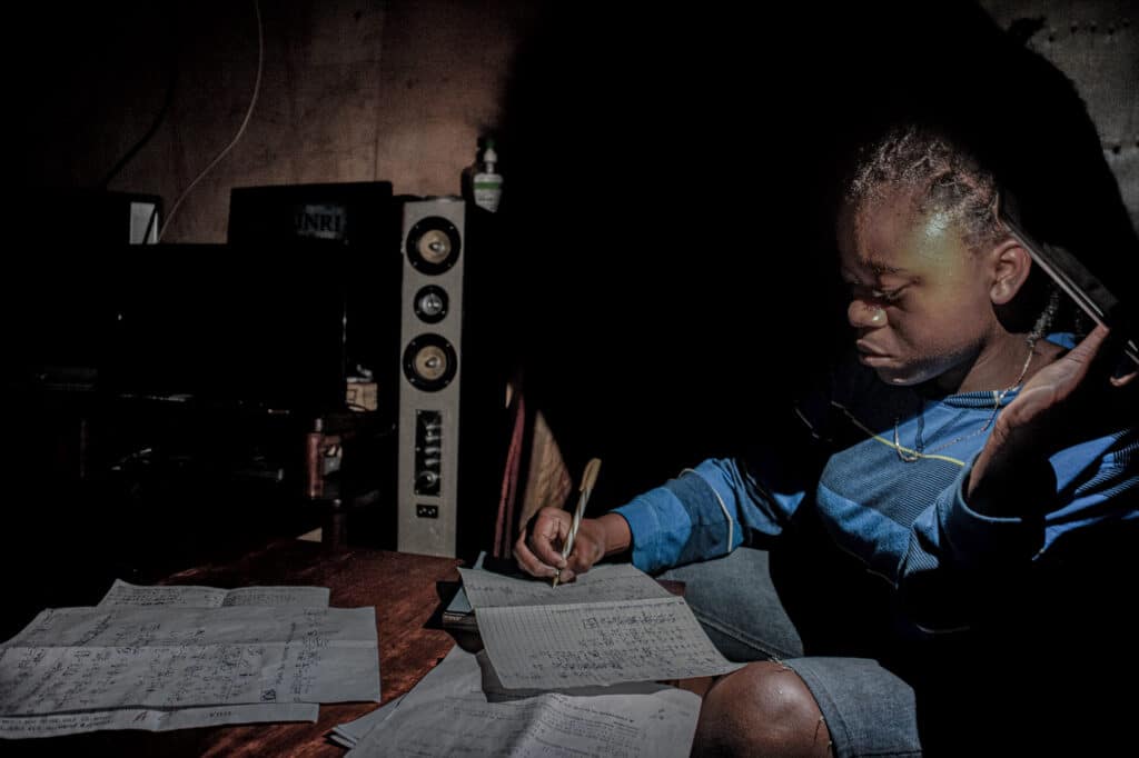 Les écoles étant fermées pendant la période de confinement au Congo, ma sœur Marie, 13 ans, étudie à la maison, à la lumière d'un téléphone portable pendant l'une des régulières coupures de courant, à Goma en début de semaine. © Arlette Bashizi / Fondation Carmignac.