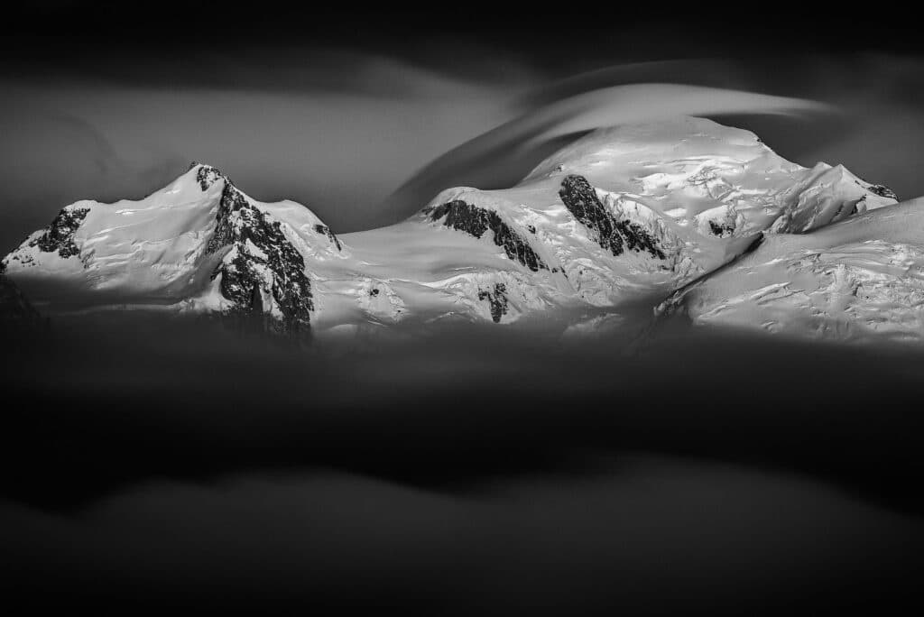 Photographie du Mont-Blanc. Le Mont-Blan sort de la mer de nuages pour recevoir les dernières lueurs du jour. Le nuage lenticulaire se forme sur son sommet lors de ces derniers instants de jours. © Thomas Crauwels