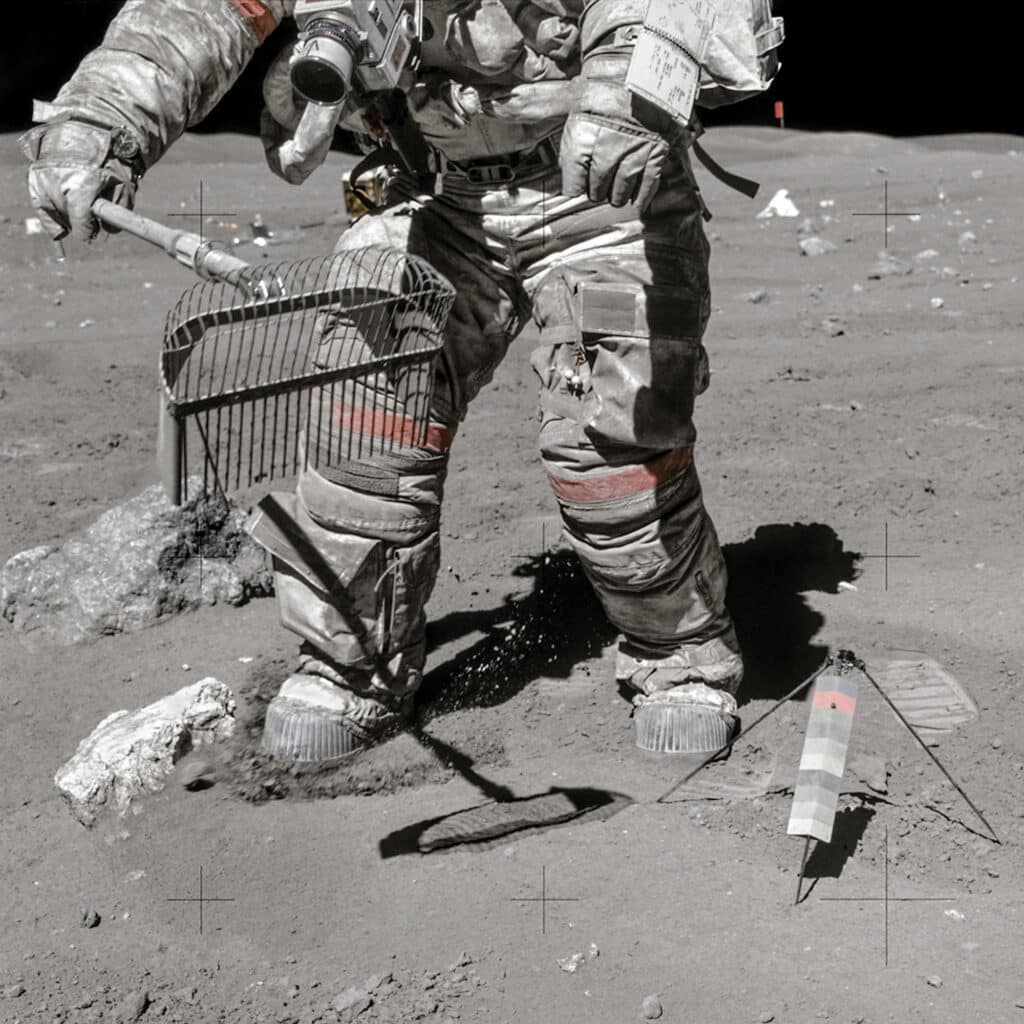 April 23, 1972 EVA 3 Hasselblad 70 mm. 60mm F/5.6 lens by Charlie Duke, NASA Ref: AS16-117-18826. Young, covered in lunar dust, prepares to use the rake to collect a sample. Of all the Apollo flight films, this photograph shows some of the finest details of the suit. Young's Omega Speedmaster watch, set to Houston time, clearly shows 1 hour, 21 minutes, and 31 seconds, which corresponds well with the time of transcription time of the mission. The array of science instruments can be seen behind him in the distance. © NASA_JSC_ASU_Andy Saunders