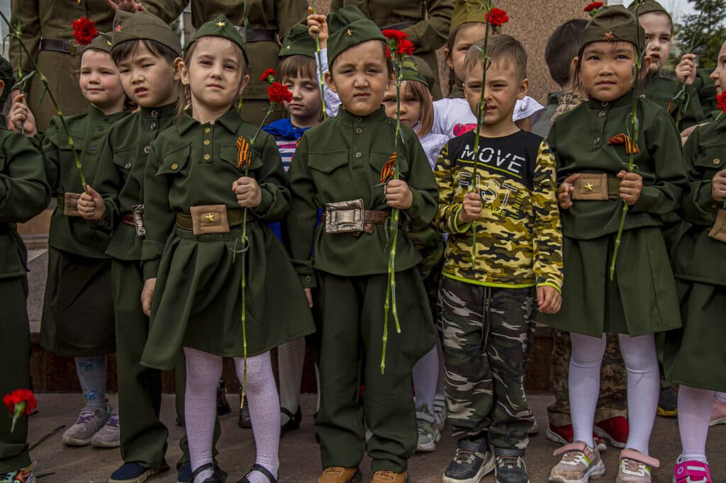 Avant de partir en vacances d’été, des écoliers se rassemblent sous la statue d’une héroïne de guerre, pour la journée de commémoration de la 2ème guerre mondiale, à Nur-sultan. © Frédéric Noy