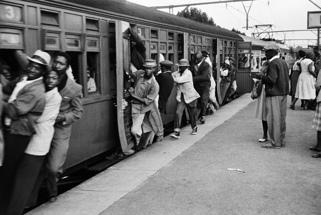 Whistle has sounded, train is moving, but people are still trying to get on © Ernest Cole