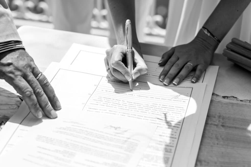 Black and white photo of bride signing wedding documents