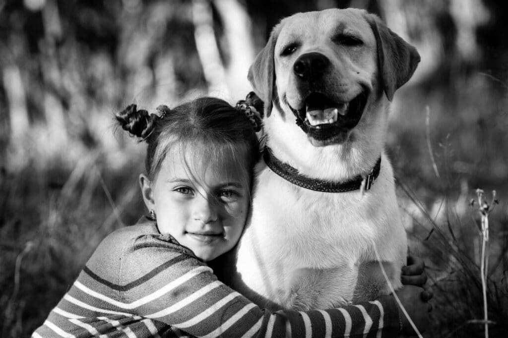 Petite fille et son chien, en plein air. Photo en noir et blanc.