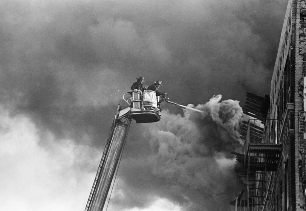 Firefighters spraying a fire in a building near Macy Place. The Bronx,1980 © Joe Conzo Jr.