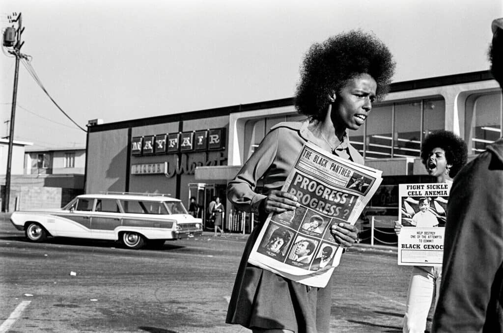 1971 - Oakland, California, USA: Black Panther Gloria Abernethy sells the Black Panther newspaper at the Mayfair supermarket boycott. Tamara Lacey holds a Sickle Cell Anemia poster. © Stephen Shames