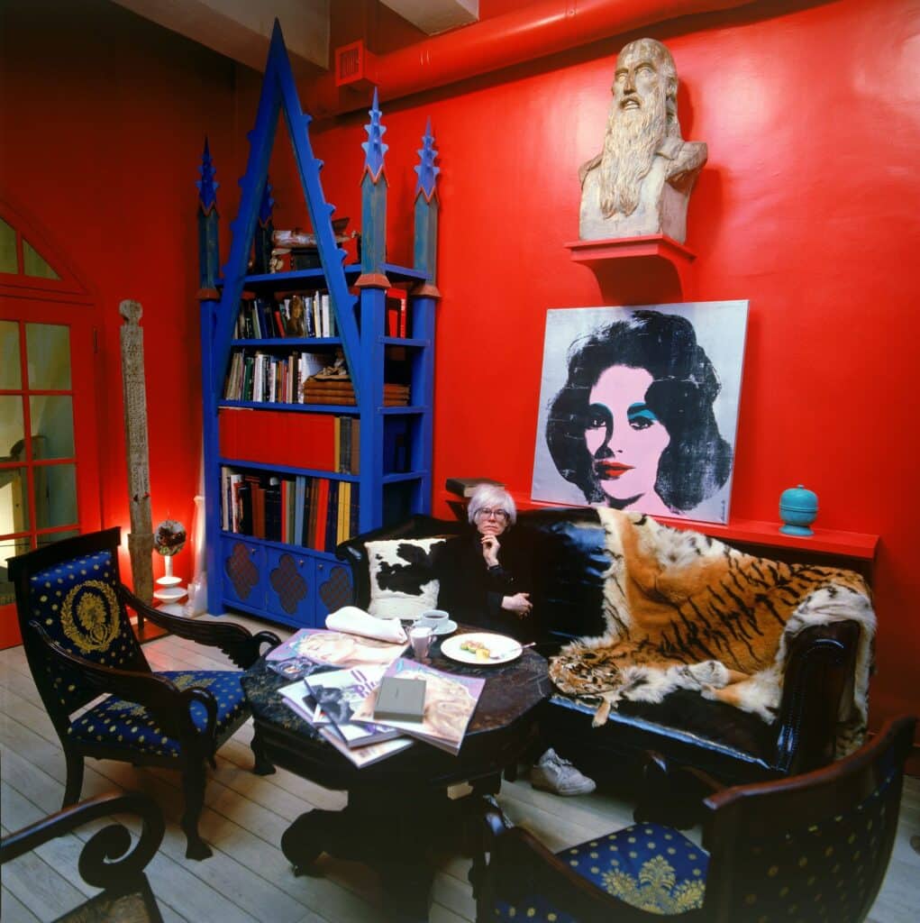 Andy Warhol with Liz Taylor’s portrait in Fred Hughes’red studio, New York, 1986. © Muna Tseng Dance Projects Inc. Courtesy Yancey Richardson Gallery, New York.