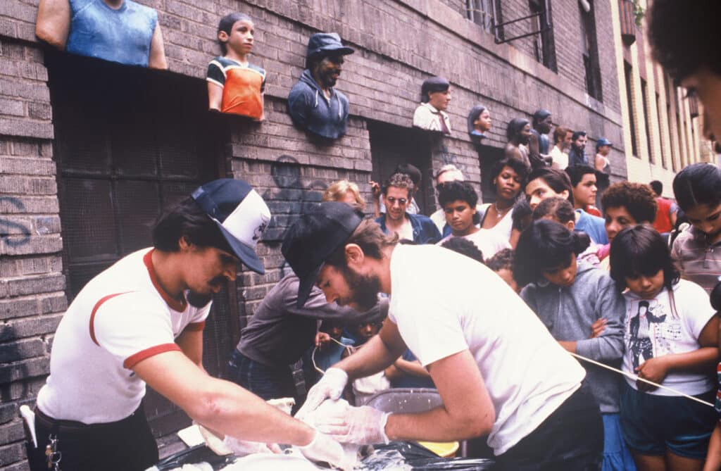 John Ahearn et Rigoberto Torres en train de réaliser un moulage lors d'une fête de quartier, Walton Avenue, Bronx, 1985.