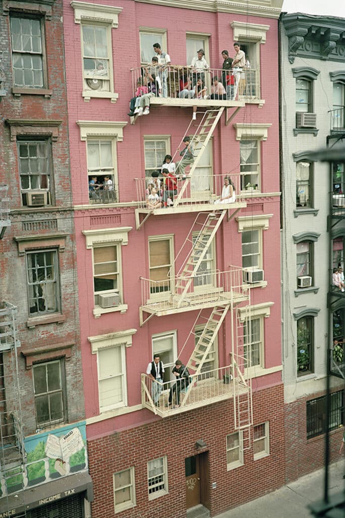 Fire Escape Viewing on Stanton Street, 1990. From the series Loisaida Street Work-1984-1990. The view from my window of 29 Clinton Street. My neighbors perch on their fire escape to watch a wrestling match taking place on the street below.