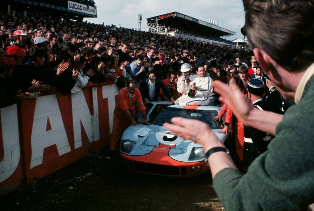 Crowds celebrate as Mexican driver Pedro Rodriguez and Belgium driver Lucien Bianchi are pushed through lines of people in their Ford GT40 car in Gulf Oil colors after claiming another victory for the manufacturer in 1968. The drivers led for 17 of the 24 hours. © Joe Honda / Le Mans Collection