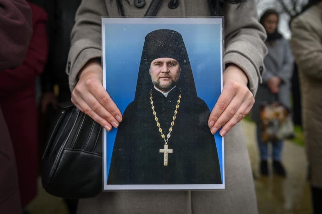 Une personne en deuil tient une photo de Myron pendant la messe de funérailles à l'extérieur de la maison familiale. 26 avril 2022, Oblast d'Ivano-Frankivsk, Ukraine.