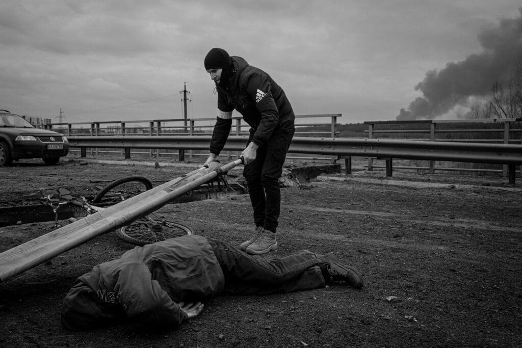 Un homme pose une civière pour récupérer le corps d'un civil tué plus tôt dans la journée sur un pont détruit utilisé pour évacuer les civils à la périphérie d'Irpin, en Ukraine, le lundi 7 mars 2022.