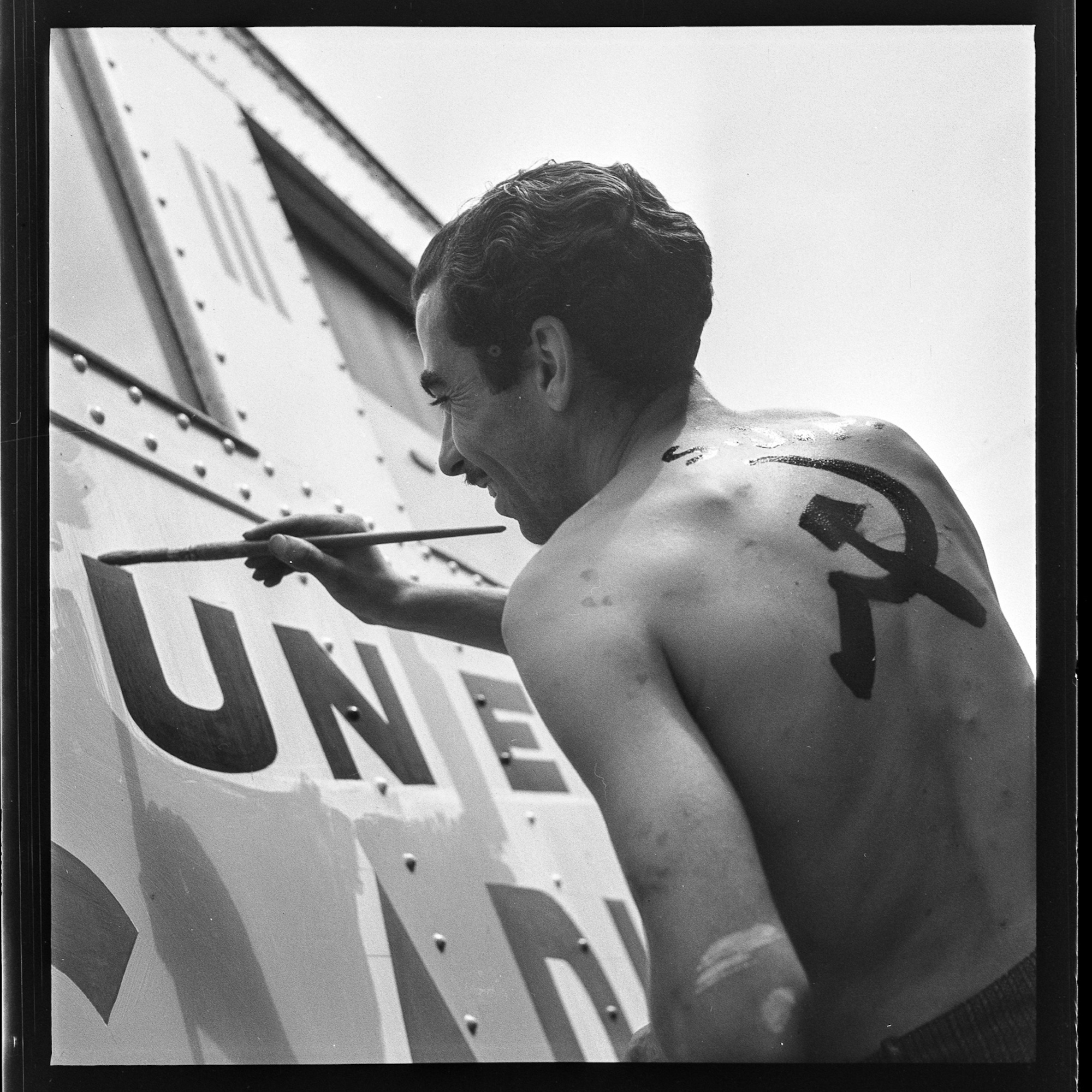 Artist Francesc Nel-lo, with sickle and hammer on his back, painting antifascist propaganda on the trains at Sant Andreu station, summer 1936 © Arxiu Campañà