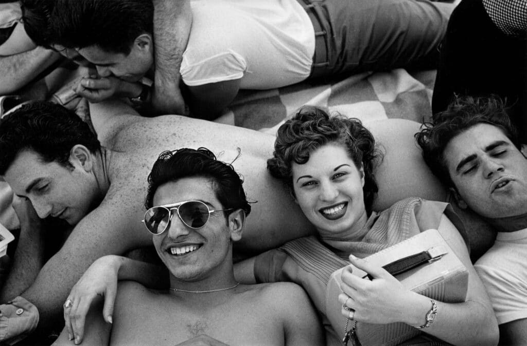 Several teenagers recline on a Coney Island beach, New York, 1949.