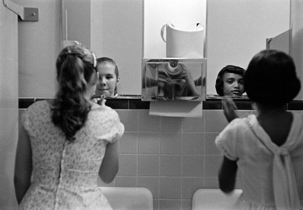 USA. Virginia. A black girl and a white girl make up in the ladies room before an integration dinner party during the civil rights strike in America. 1958.