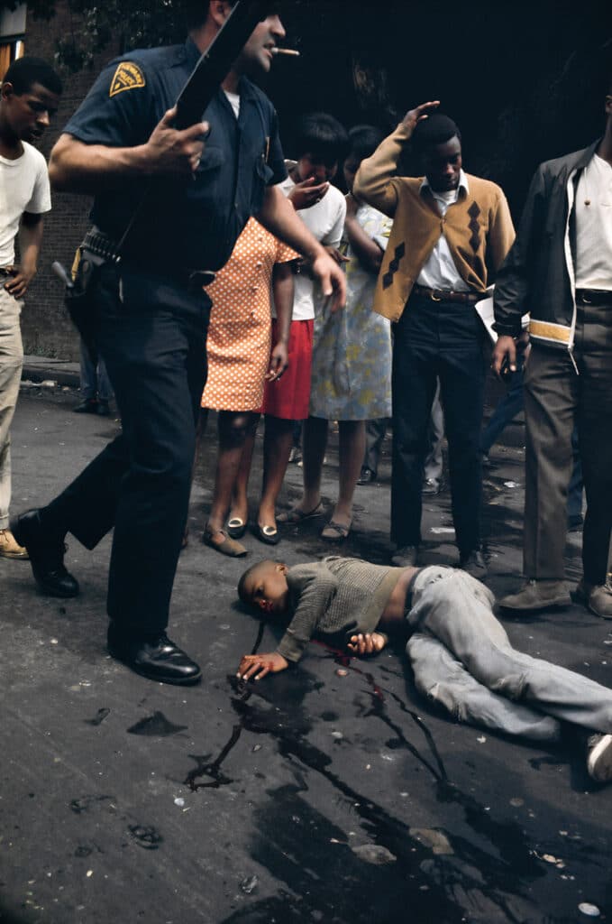 Joey Bass Jr lies wounded on the street as Officer Scarpone, one of the Newark policemen whose bullets hit him, stands over - photo credit, Bud Lee