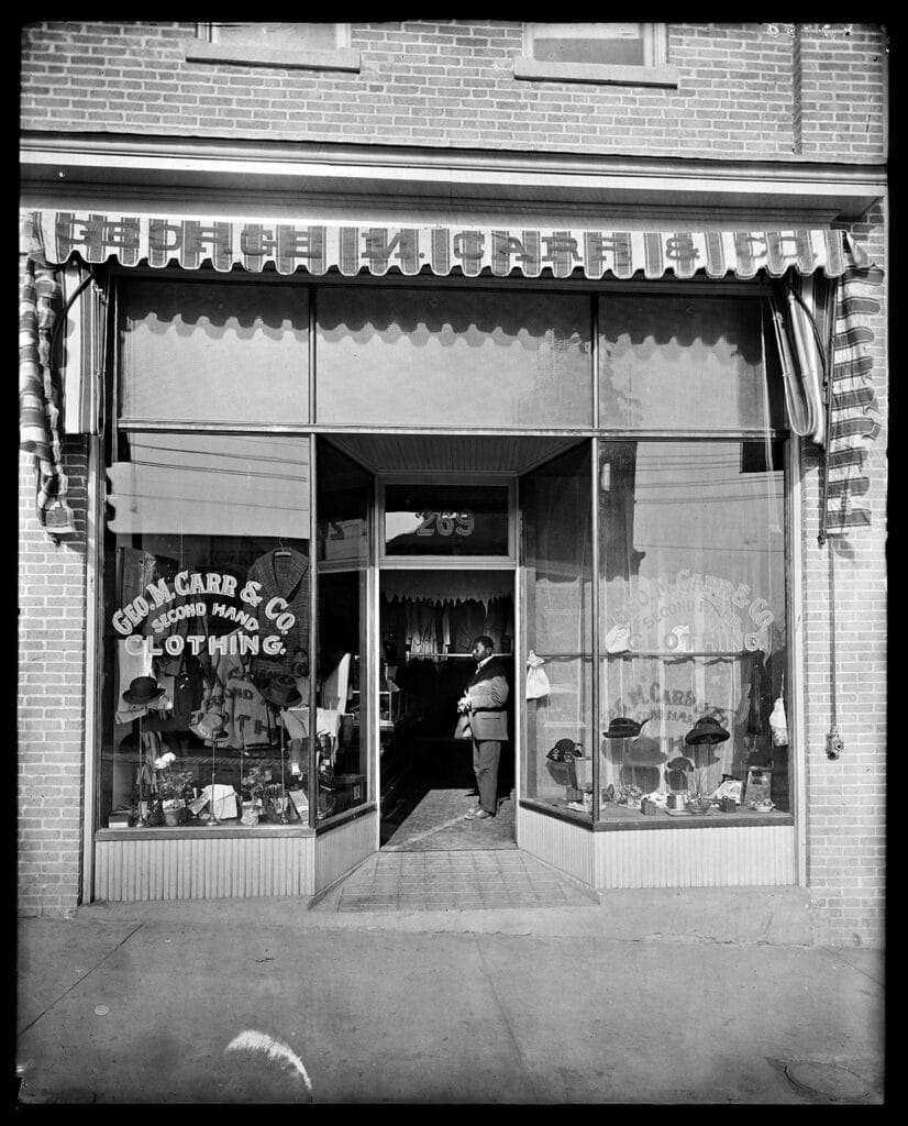 George Carr, debout dans l'entrée de son magasin de vêtements d'occasion, Holsinger Studio Collection. © Bibliothèque des collections spéciales Albert et Shirley Small, Université de Virginie.