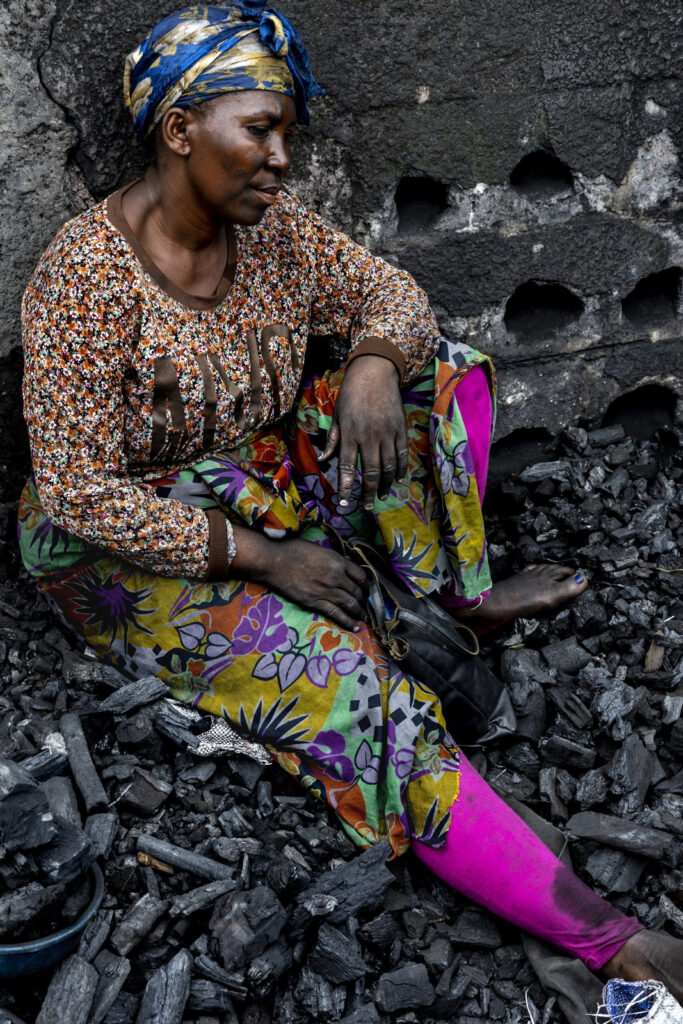 RDC, 2021. Kinshasa, commune de N’Djili. Au marché Pascal, les femmes qui vendent le charbon de bois travaillent dans de terribles conditions, assises à même le sol, le visage couvert de suie. © Pascal Maitre / MYOP