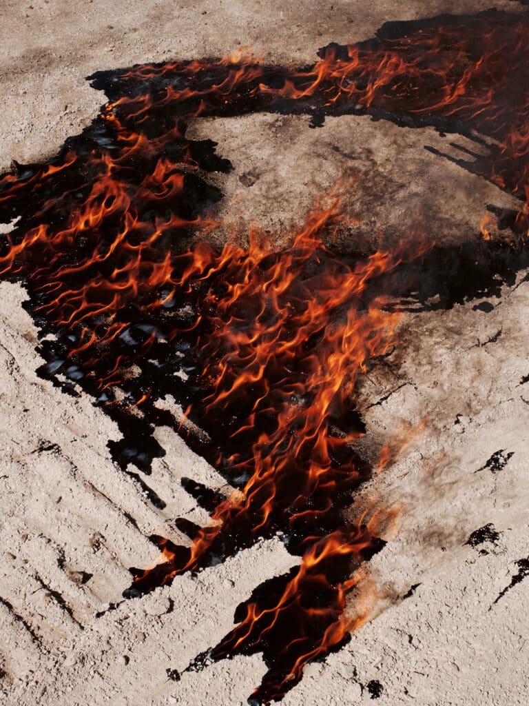 A fire seen near a gas station after people took their belongings and left their city behind, during the last days of Hasankeyf. The historic city and its 12,000 years old monuments (not moved to the archaeological park) are engulfed since spring 2020, while the city was a protected natural area since 1981. This fate is caused by the Ilisu dam project of the government. Turkey, Hasankeyf. 2020 © Emin Özmen