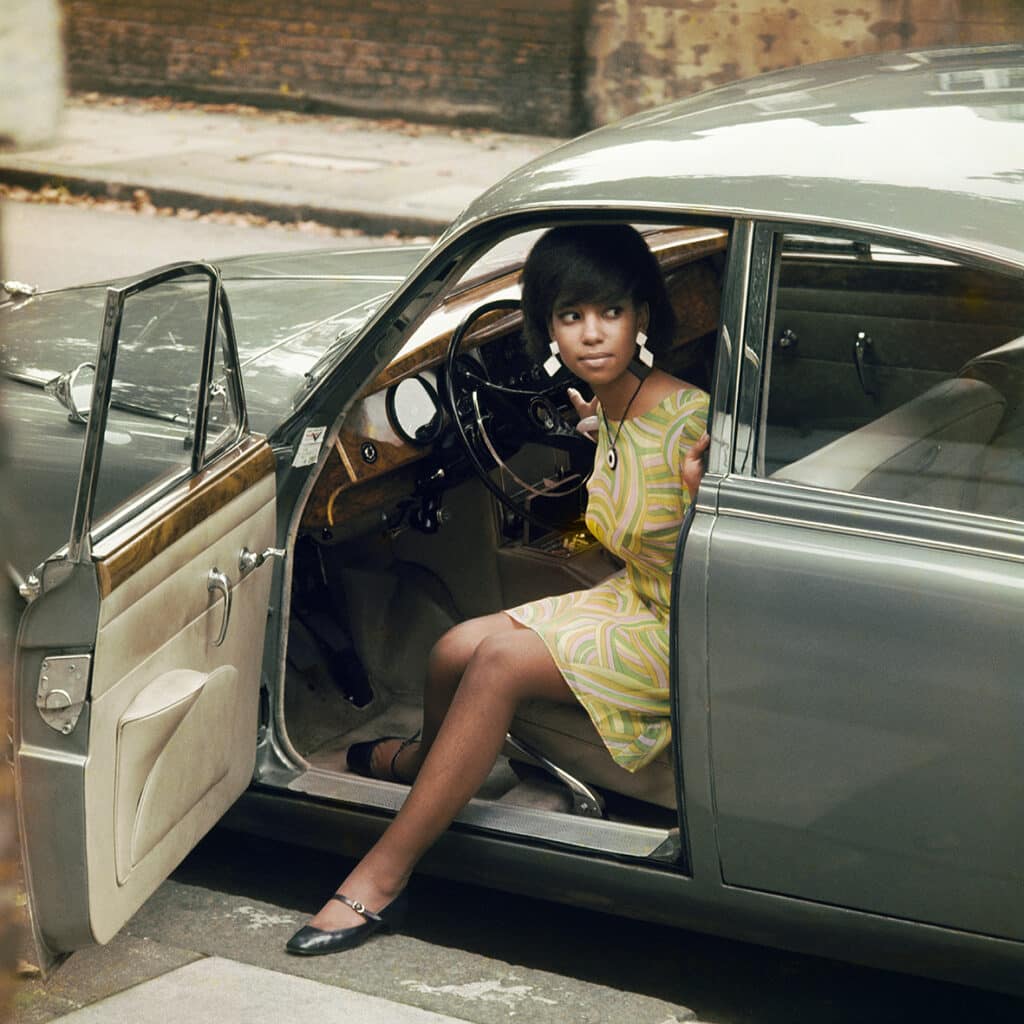 James Barnor b. 1929 Drum cover girl Erlin Ibreck stepping out of a Jaguar in Kilburn, London, 1966 Printed in 2023 Lambda C-Print 70 x 70 cm